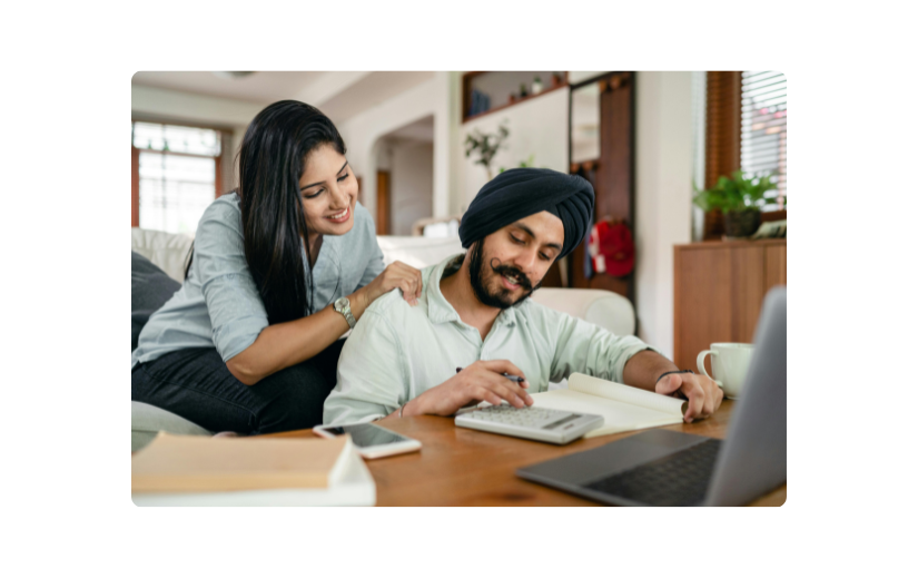 A happy couple working on finances at home with a laptop and calculator, exploring low-cost startup ideas for online biz.